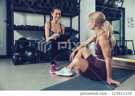 Blonde woman having a conversation with her coach after workout in gym Blonde woman having a conversation with her coach after workout in gym 125621329