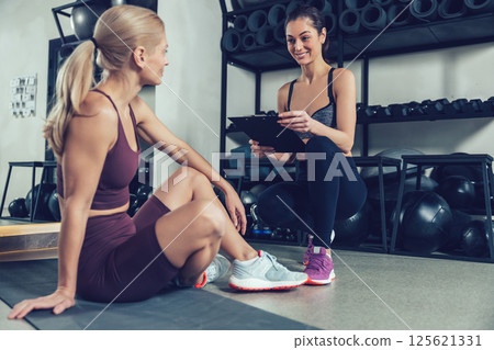 Blonde woman having a conversation with her coach after workout in gym Blonde woman having a conversation with her coach after workout in gym 125621331
