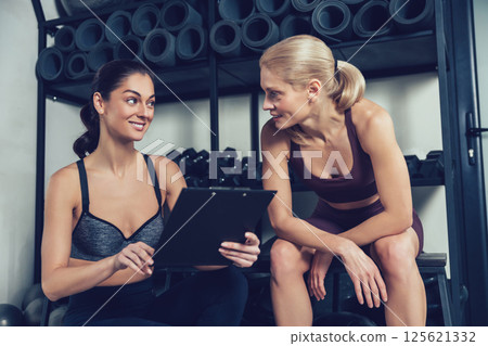 Blonde woman having a conversation with her coach after workout in gym Blonde woman having a conversation with her coach after workout in gym 125621332