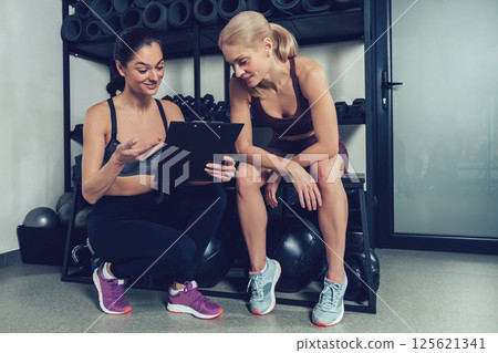 Blonde woman having a conversation with her coach after workout in gym 125621341