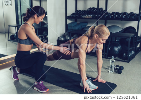 Young female coach training a young woman in the gym 125621361
