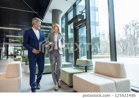 Businesswoman and businessman walking in office talking about corporate partnership and teamwork 125621486