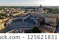Stunning aerial view of St. Peter's Basilica and St. Peter's Square in Vatican City at sunset, surrounded by historic architecture and lush greenery 125621831