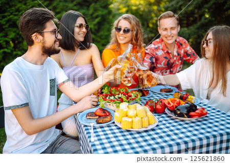 Group of young friends having picnic toasting with beer in nature. Lifestyle, relaxation concept. 125621860
