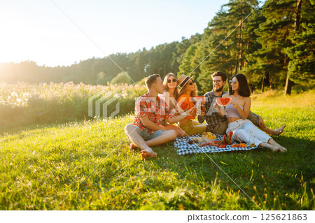 Group of people gathered in garden for picnic. Friends have fun and drink beer. Picnic, friendship. 125621863