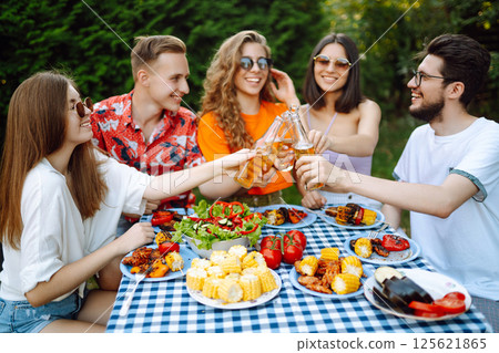 Happy friends in picnic in park. Friends grill meat, have fun, relax. ?oncept of holidays, weekends. Happy friends in picnic in park. Friends grill meat, have fun, relax. ?oncept of holidays, weekends. 125621865