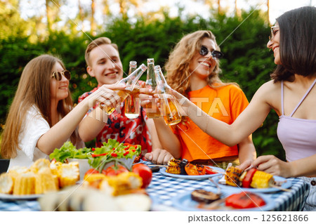 Happy friends in picnic in park. Friends grill meat, have fun, relax. ?oncept of holidays, weekends. 125621866