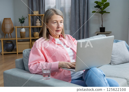 Mid aged woman in pink shirt feeling unwell and having a headache 125622108