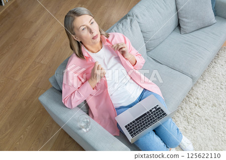 Mid aged woman in pink shirt feeling unwell and having a headache 125622110