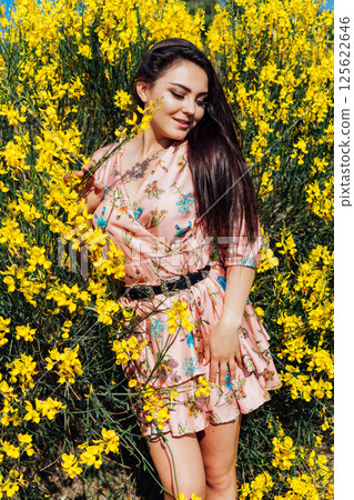 woman in summer dress inhales the aroma of spring flowers woman in summer dress inhales the aroma of spring flowers 125622646