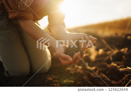 Woman farmer's hand touch soil, check its health before growing plants, seeds. Agriculture concept 125622649