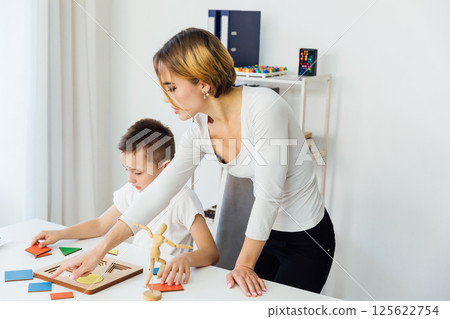 Female teacher playing educational games with boy at table in classroom 125622754