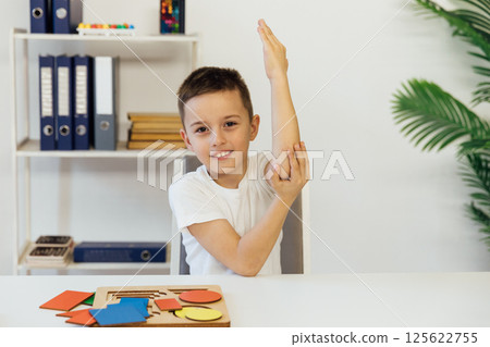 A schoolboy raised his hand up to answer in a classroom A schoolboy raised his hand up to answer in a classroom 125622755
