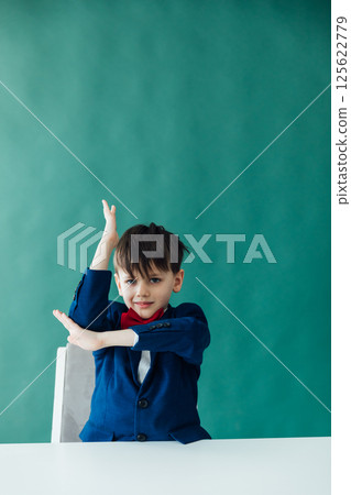 A school boy stretches his hand for an answer on the desk A school boy stretches his hand for an answer on the desk 125622779