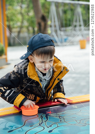 Boy playing air hockey in children's park Boy playing air hockey in children's park 125622988