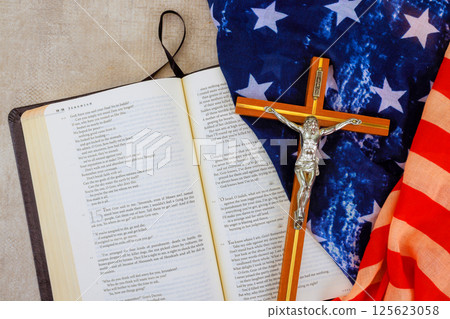 24 April 2025 Washington DC US Bible opened to page with crucifix folded flags placed nearby, blending faith patriotism in one view. 24 April 2025 Washington DC US Bible opened to page with crucifix folded flags placed nearby, blending faith patriotism in one view. 125623058