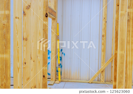 Construction of wooden frame structure is underway is vertical beams with level tool 125623060
