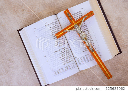 24 April 2025 Jerusalem Israel Cross rests on pages of an open Hebrew Holy Bible, emphasizing faith and spirituality in Messianic Jewish Congregation during prayer time "Hebrew Tanakh prayer holy book 125623062