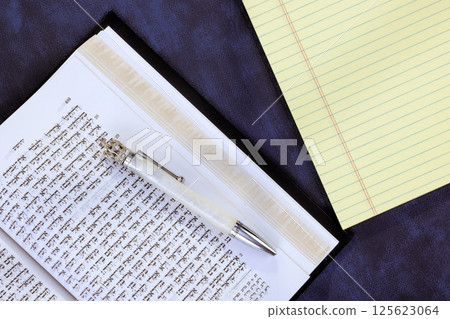24 April 2025 Jerusalem Israel Notepad, silver pen sit beside an open Hebrew Tanakh book symbolizing Messianic Jewish Congregation "Hebrew Tanakh prayer holy book" 125623064