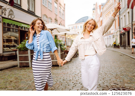 Two beautiful women are walking down the street. Fun and walking concept. Active lifestyle. 125623076