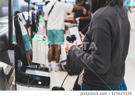 Woman self check in with hand scanning barcode in the airport. Woman self check in with hand scanning barcode in the airport. 125623330