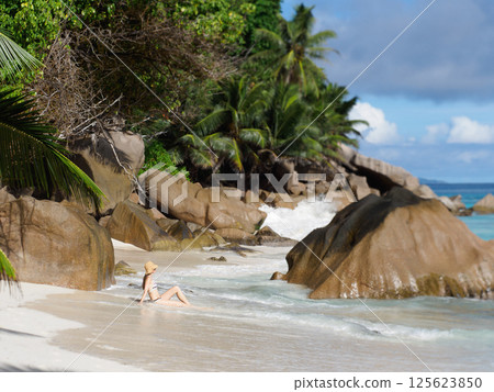 Cute woman sitting on stunning white sand beach 125623850