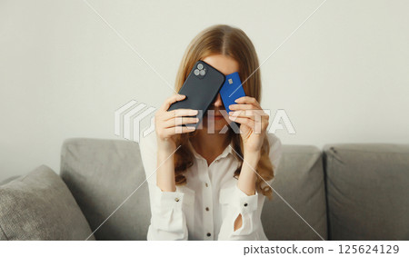Upset young woman with smartphone, credit bank card, internet fraud, problems with online payments Upset young woman with smartphone, credit bank card, internet fraud, problems with online payments 125624129