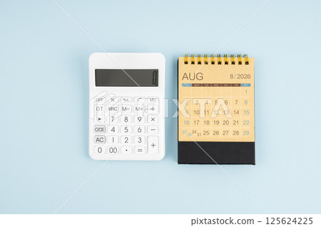 August 2026 desk calendar and calculator on blue background. 125624225