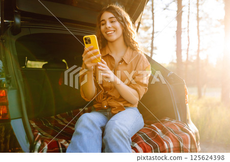 Young woman enjoys a sunny day outdoors while sitting in her car. Travel, weekend, nature, relax Young woman enjoys a sunny day outdoors while sitting in her car. Travel, weekend, nature, relax 125624398