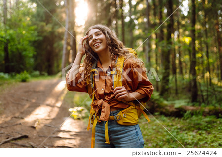 Tourist woman hiking alone in thick autumn forest. Stylish female looks for pathway among trees. Tourist woman hiking alone in thick autumn forest. Stylish female looks for pathway among trees. 125624424