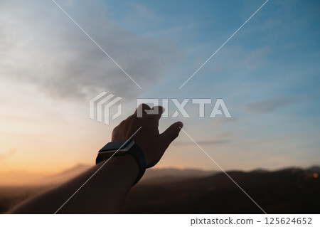 Hand reaching toward the evening sky during sunset in Andalusia 125624652