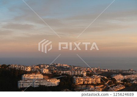 Golden hour light over Mediterranean hillside town in Costa del Sol 125624689