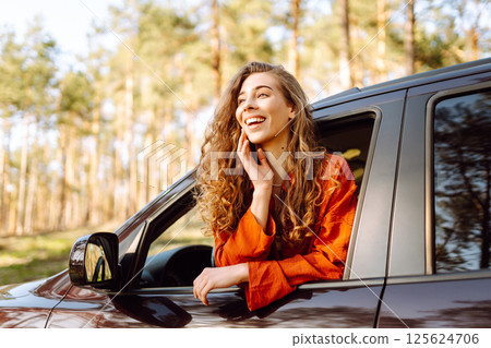 Young woman leaning out of the car window enjoying nature. Road trips summer holidays. 125624706