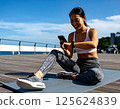 一名女子在瑜珈墊上使用智慧型手機管理自己的健康狀況。人工智慧生成的 125624839