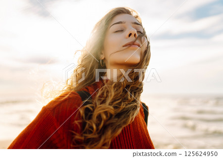 As she walked along the beach, the woman tourist adjusted her backpack, taking in the salty sea air 125624950