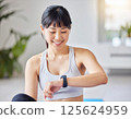 一名女子在瑜珈墊上使用智慧型手機管理自己的健康狀況。人工智慧生成的 125624959