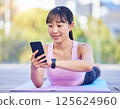 一名女子在瑜珈墊上使用智慧型手機管理自己的健康狀況。人工智慧生成的 125624960