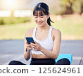 一名女子在瑜珈墊上使用智慧型手機管理自己的健康狀況。人工智慧生成的 125624961