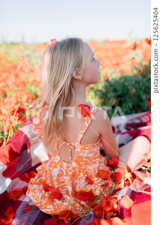 Child girl in blooming poppy field, summer day 125625404