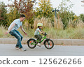 Quality Time Together Father Teaching Daughter to Ride a Bike Outdoors 125626266