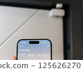 A close-up of a smartphone displaying a smart home interface, showing real-time security status with Door Sensor in Background 125626270