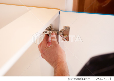 Installing a furniture hinge on the door. Assembling furniture and fixing fittings 125626291