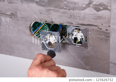 Home electrical repair in progress with tools and wiring on the wall Home electrical repair in progress with tools and wiring on the wall 125626732