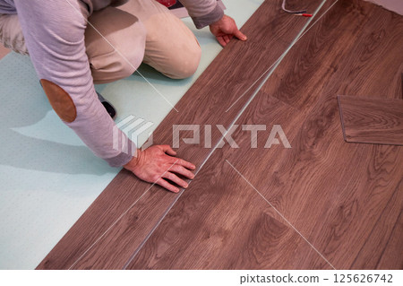 A worker installs laminate or quartz vinyl tile flooring 125626742