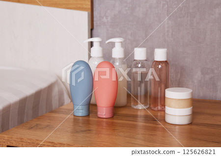 Compact bottles for cosmetics and hygiene products on the bedside table in the hotel room Compact bottles for cosmetics and hygiene products on the bedside table in the hotel room 125626821