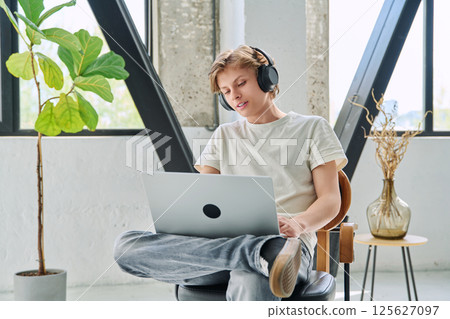 Teenage boy with headphones using laptop for video conference, online meeting 125627097