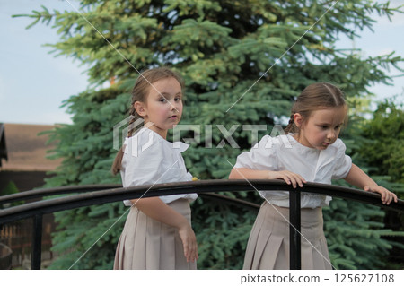 Two little sisters stand side by side, completely absorbed in the moment. Each braid mirrors the other. Two little sisters stand side by side, completely absorbed in the moment. Each braid mirrors the other. 125627108