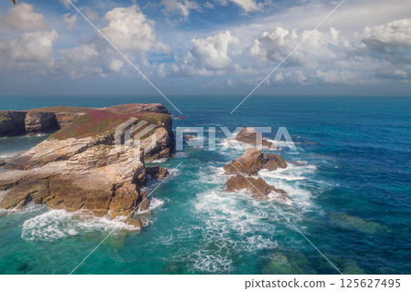 Seascape on a sunny day. Rocks in the ocean. Beach Praia Dos Castros, Ribadeo, Galicia, Spain Seascape on a sunny day. Rocks in the ocean. Beach Praia Dos Castros, Ribadeo, Galicia, Spain 125627495