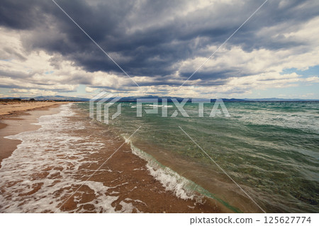 Seascape with the dramatic cloudy stormy sky. Deserted beach in windy weather 125627774