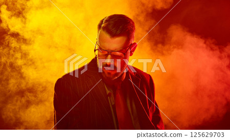 Man in suit lowers head with eyes closed in saturated red light suggesting emotional surrender Man in suit lowers head with eyes closed in saturated red light suggesting emotional surrender 125629703